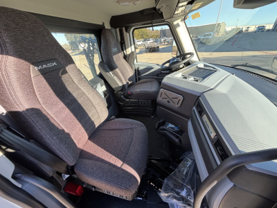 Interior of a new 2027 Mack PR64T daycab truck cab, showing driver and passenger seats, steering wheel, dashboard, and center console.