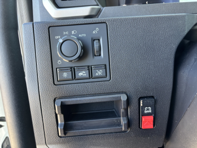 Dashboard control panel with circular dial and multiple switches in a Mack PR64T cab showing headlight and dimmer controls.