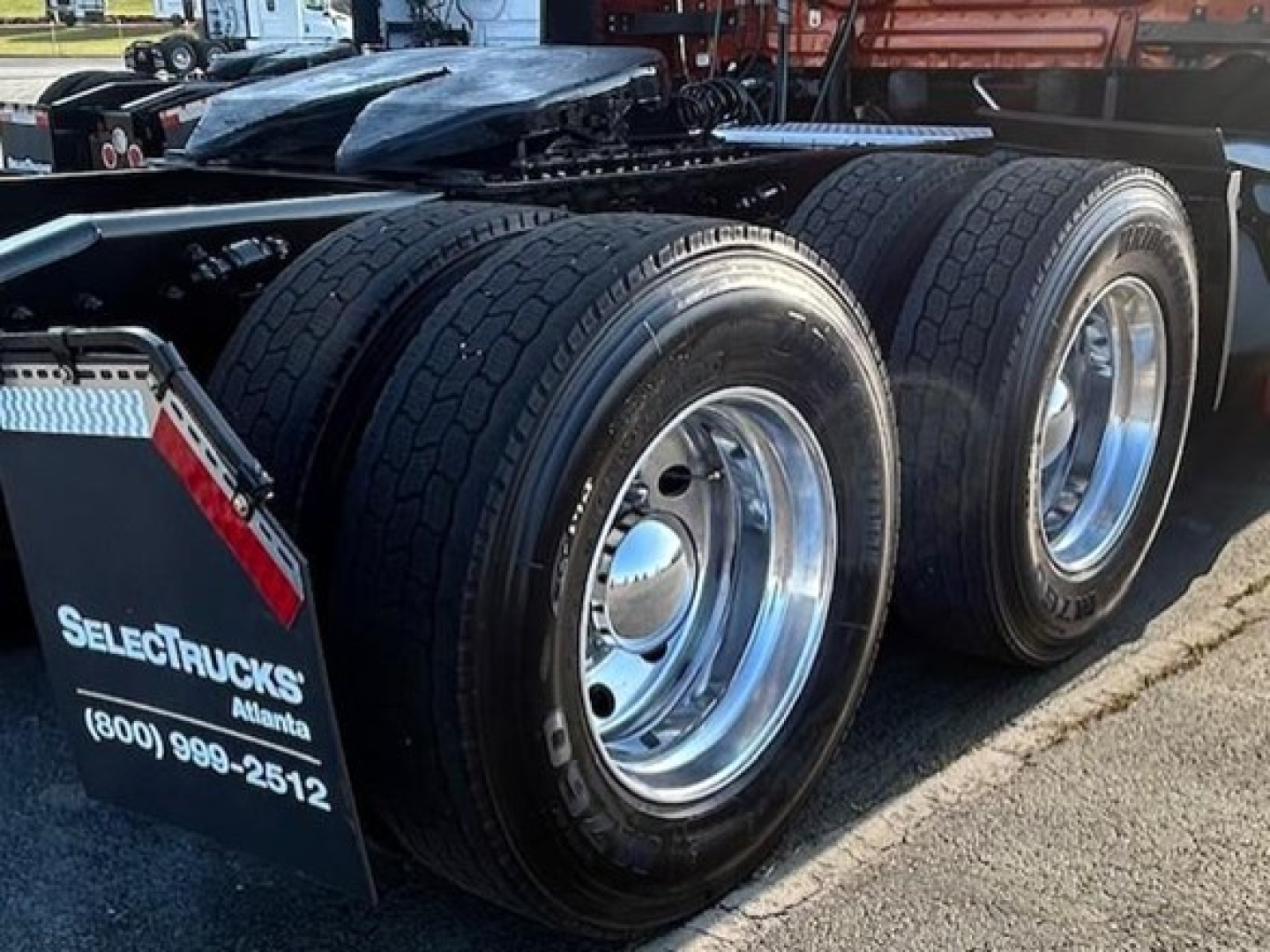 Axle dual rear wheels and touring trailer under Freightliner Cascadia 126 truck in a dealership lot.