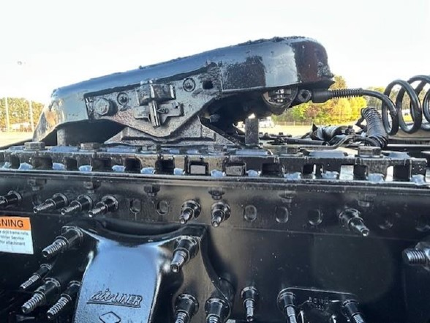 Tractor-trailer engine area showing valve covers, hoses, and frame components of a Freightliner Cascadia 126. Includes air intake and mounting hardware along with warning sticker and connectors.