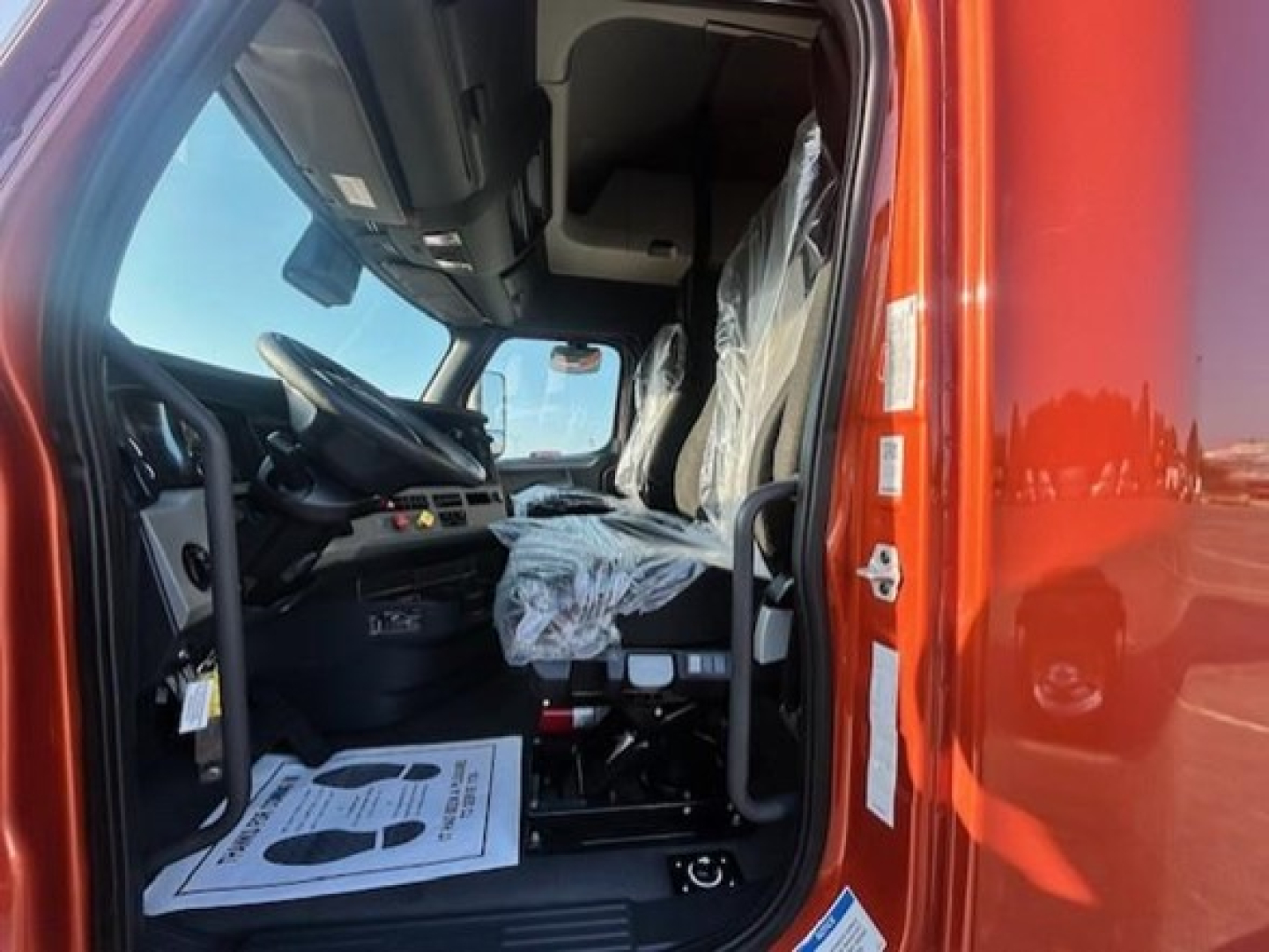Cab interior of a Freightliner Cascadia truck showing driver's seat, steering wheel, and dashboard inside the cab.