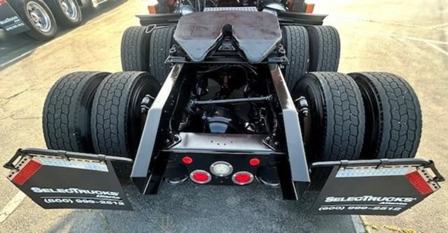 Rear view of a Freightliner Cascadia tractor showing dual rear axles and fifth wheel with mud flaps and tire configuration.