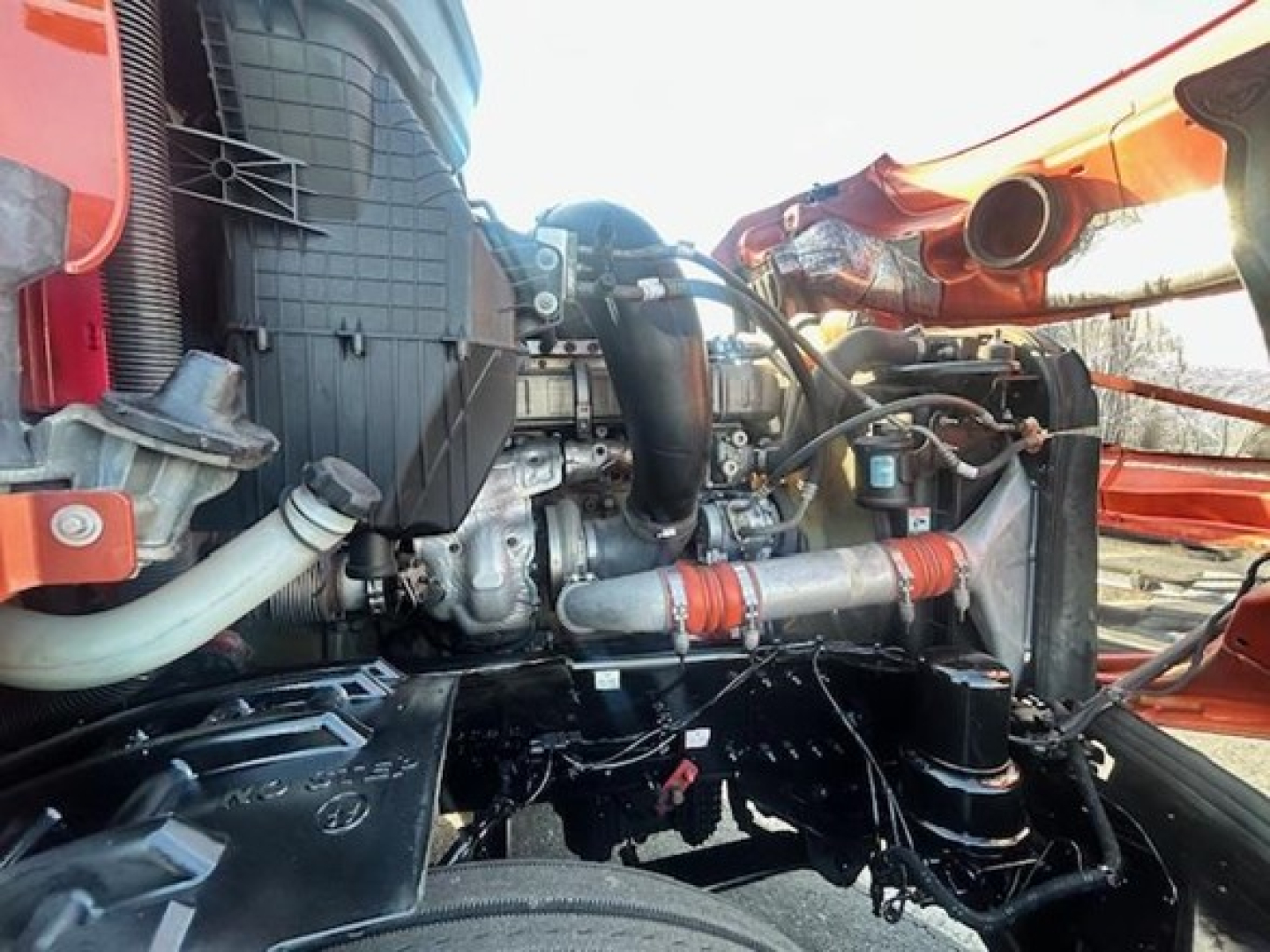 Truck engine bay view showing components such as turbo/air intake, hoses, clamps, and coolant lines in a Freightliner Cascadia engine bay.