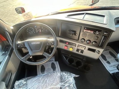 Truck cab dashboard and steering wheel of a Freightliner Cascadia 126, with instrument cluster, center console, and steering column visible.