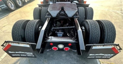 Rear view of a Freightliner Cascadia tractor showing dual rear axles and fifth wheel with mud flaps and tire configuration.