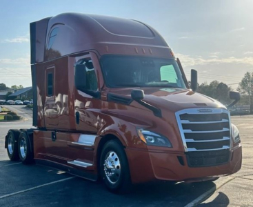 Freightliner Cascadia 126 sleeper tractor in brown showing side mirrors, chrome grille, and triple rear axles.