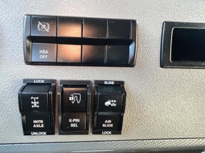 Dashboard control panel with labeled switches: HSA OFF, LOCK, INTR AXLE, UNLOCK, K-PIN REL, SLIDE, AIR SLIDE LOCK, and icons.