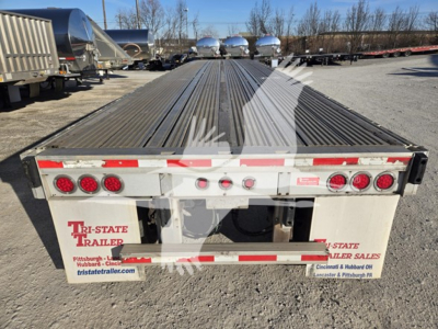 Flatbed trailer rear view showing linkage, taillights, and reflective tape; Tri-State Trailer Sales logo on mud flaps and plate area; long corrugated steel deck, VIN 1RNF48A24FR032383.