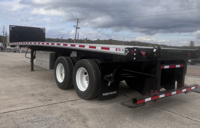 Flatbed trailer showing dual rear axles and black frame with white rims, Fontaine branding on the mudflaps, and-frk lift kit area visible.