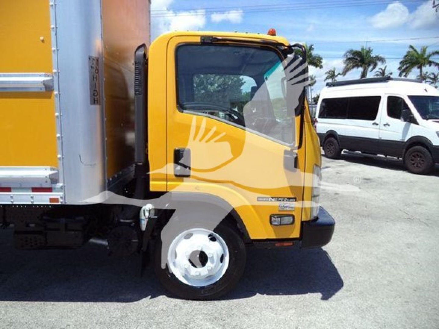 Isuzu NPR-HD box truck cab side view showing yellow cab and black bumper, front wheel, and part of cargo box.