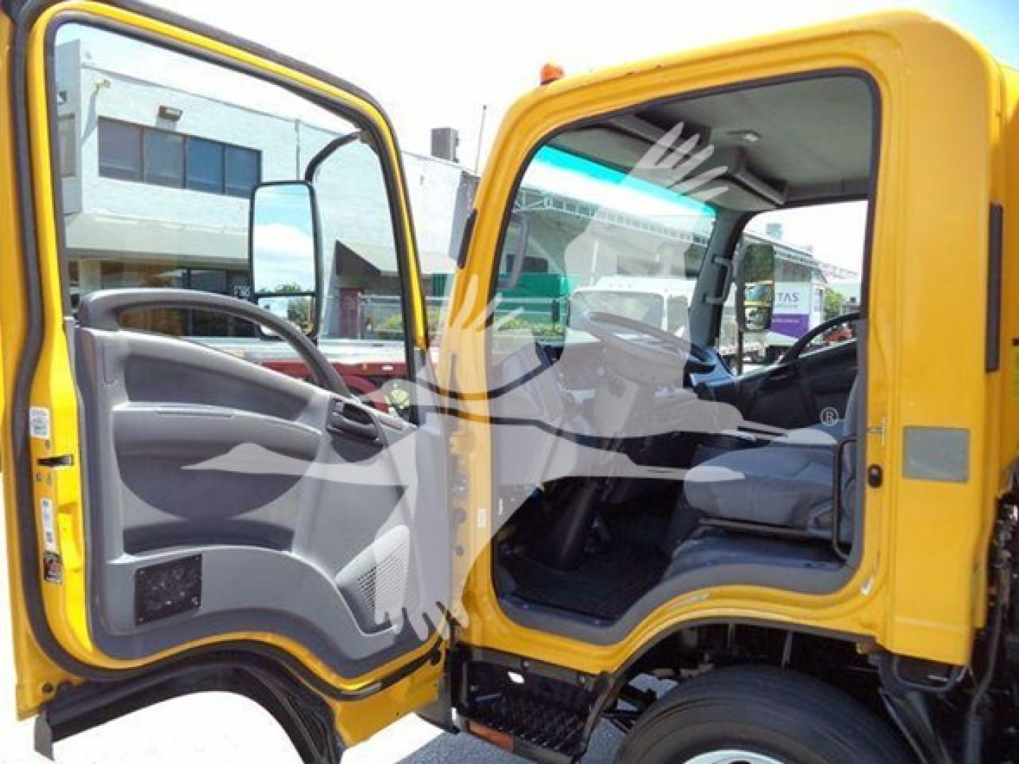Isuzu NPR HD truck cab interior and doorway showing yellow exterior and open door with gray dashboard and steering wheel.