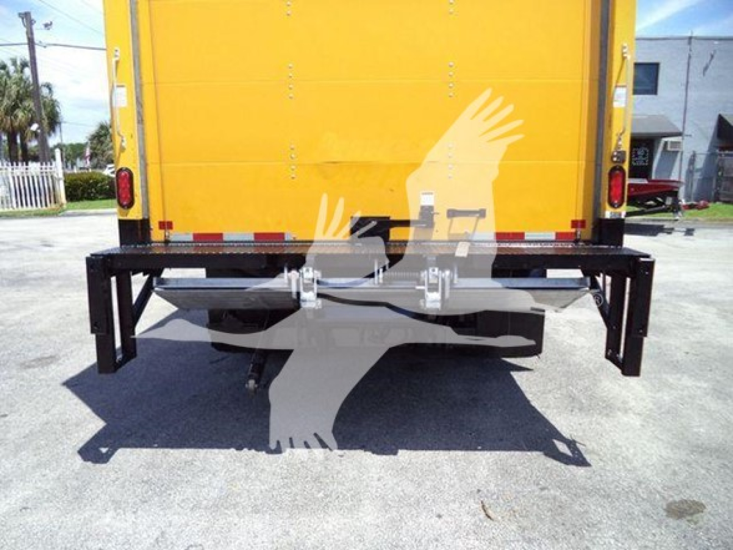 Back view of a yellow Isuzu NPR-HD box truck showing a heavy-duty metal rear bumper guard and hitch attachments.