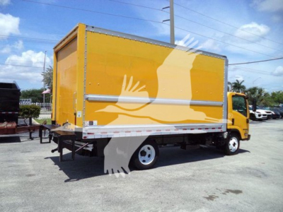 Isuzu NPR HD box truck in yellow with cargo box, side view showing rear lift gate and dual rear wheels.