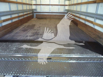 Interior of a box truck cargo area showing wooden floor and metal diamond plate threshold with a graphic overlay.