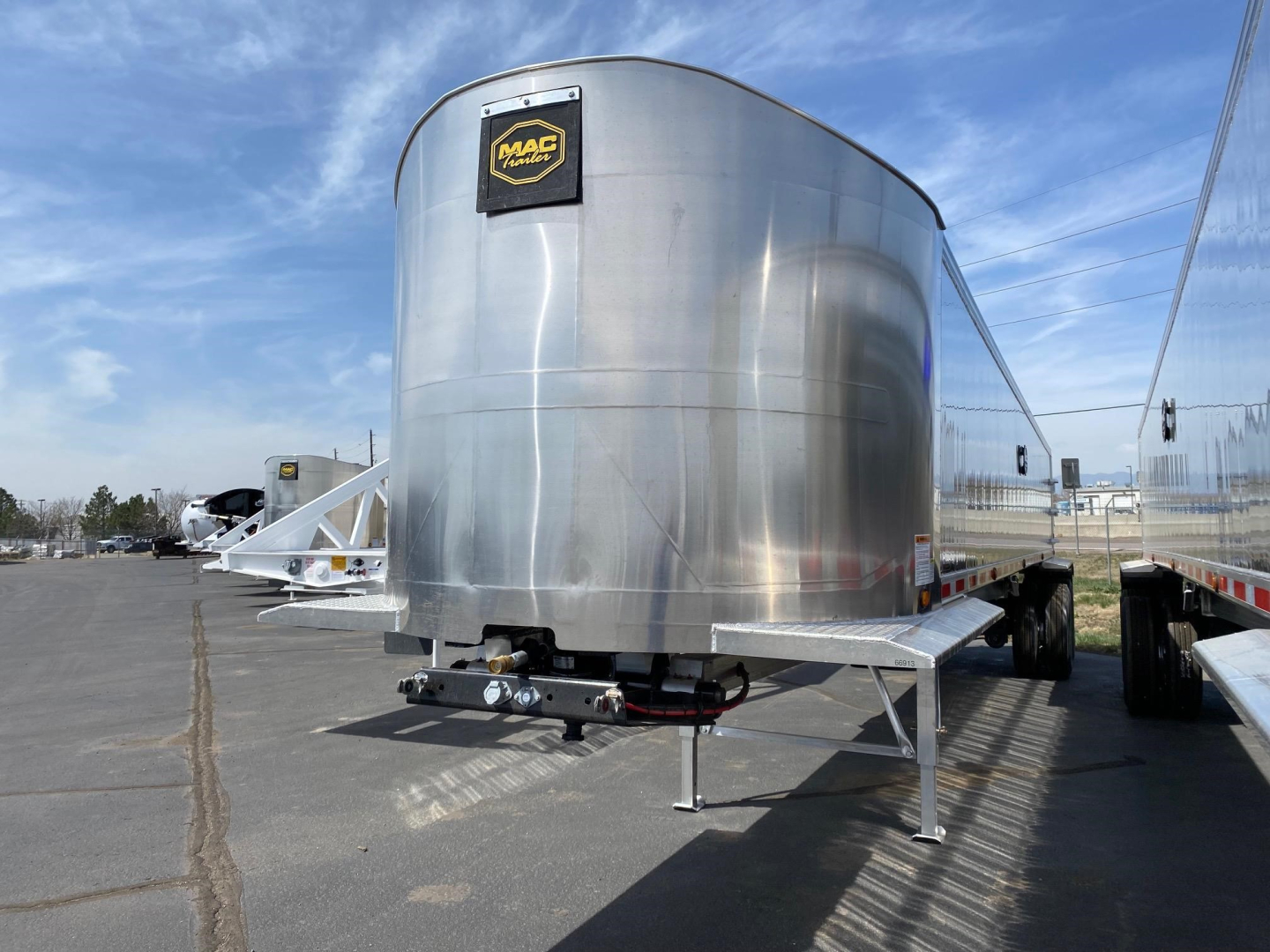 Mac Trailers by Wes showing aluminum dump trailer nose with MAC Logo plaque on front and dual-axle configuration.