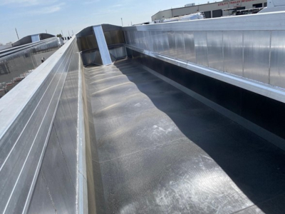 Trailer bed interior view showing metal sidewalls and a smooth aluminum floor with raised ribbed edges, reflections on the metal surfaces.