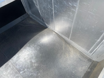 Dump trailer interior corner showing metal floor with wear and seam joints in aluminum paneling.