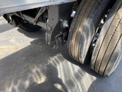 Trailer undercarriage showing dual rear tires and suspension components with a bracket and leaf-spring area visible.