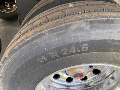 Trailer tire mounted on rim with visible sidewall text 'HR 24.5' and wheel hub with red emblem.