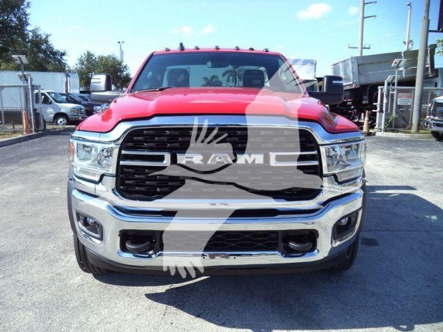 Front view of a red 2024 Ram 5500 SLT truck in a dealership lot, with large black grille, chrome bumper, and RAM emblem visible.