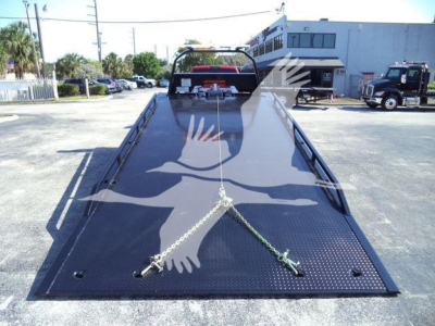 Ram 5500 rollback flatbed truck in service bay showing dual chains and diamond plate bed.