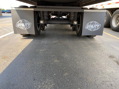 Trailer undercarriage showing dual fenders with Utility logos and rear axle assembly viewed from ground level.