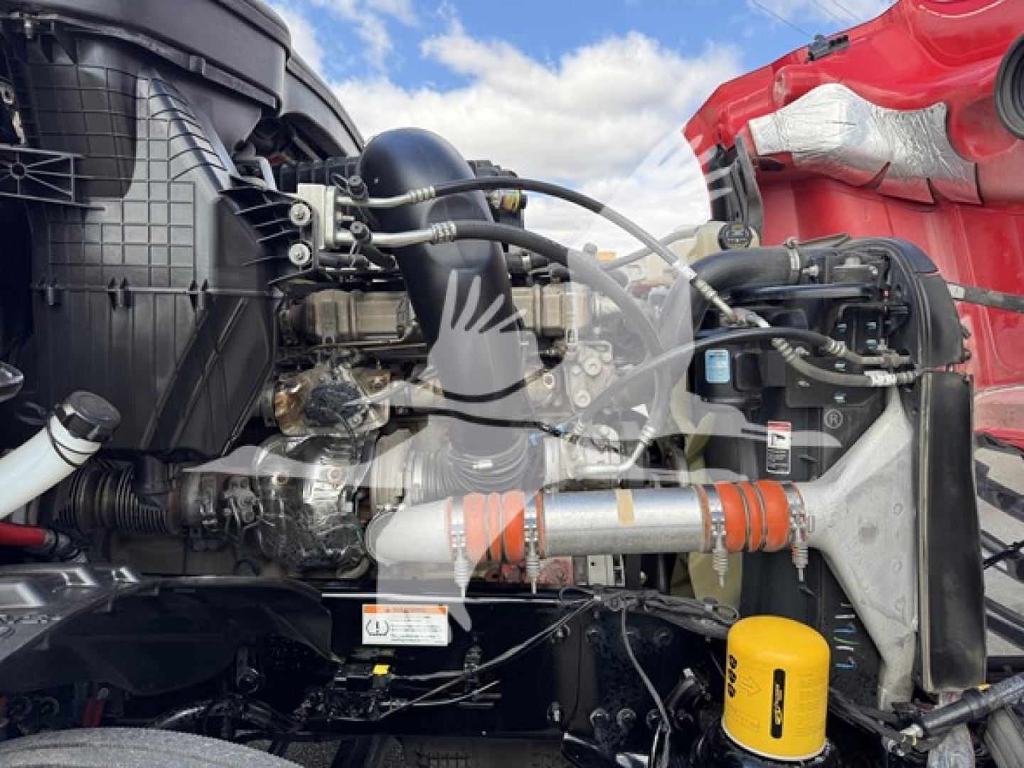 Diesel engine bay of a 2023 Freightliner Cascadia 126 showing engine components, intake piping, hoses, and yellow oil filter cap.