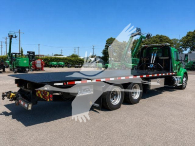 Kenworth T370 rollback tow truck with a flatbed, green cab, and triple rear wheels shown in a dealership lot