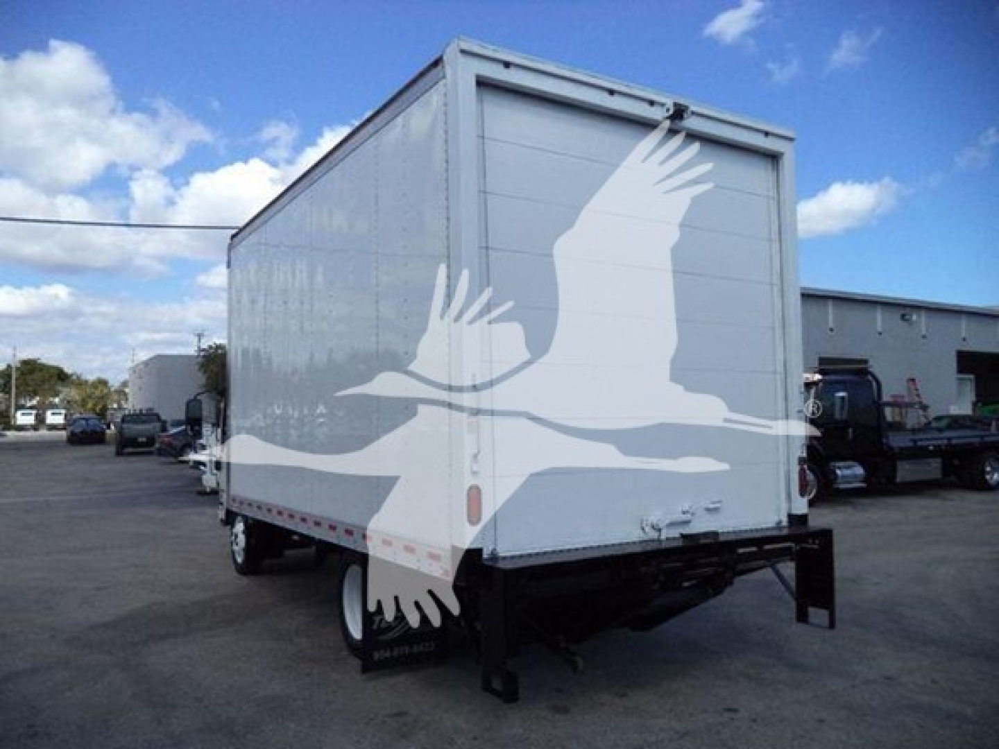 Isuzu NPR HD box truck trailer rear view showing white cargo box and dual rear doors.