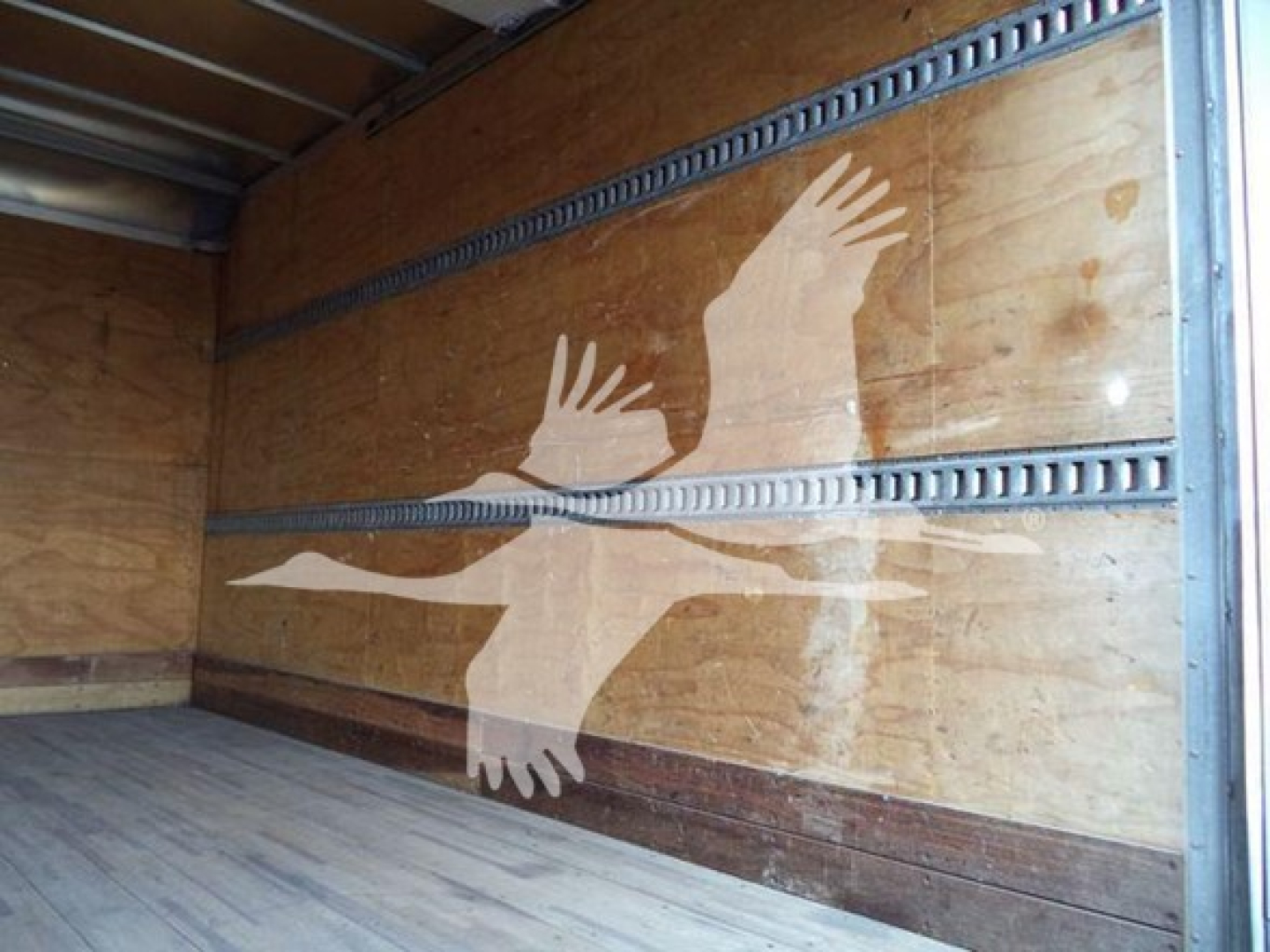 Isuzu NPR HD truck cargo area with wooden walls and a mural of a bird in flight on the side.
