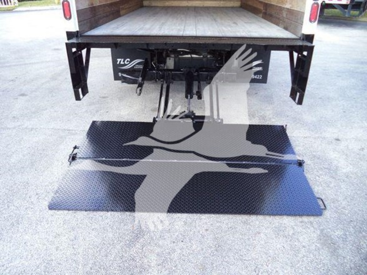 Isuzu NPRHD truck bed with fold-down wheelchair or ramp access plate extended on diamond plate surface.