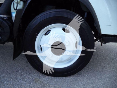 Isuzu NPR HD truck front wheel showing steel rim and tire, part of box truck.