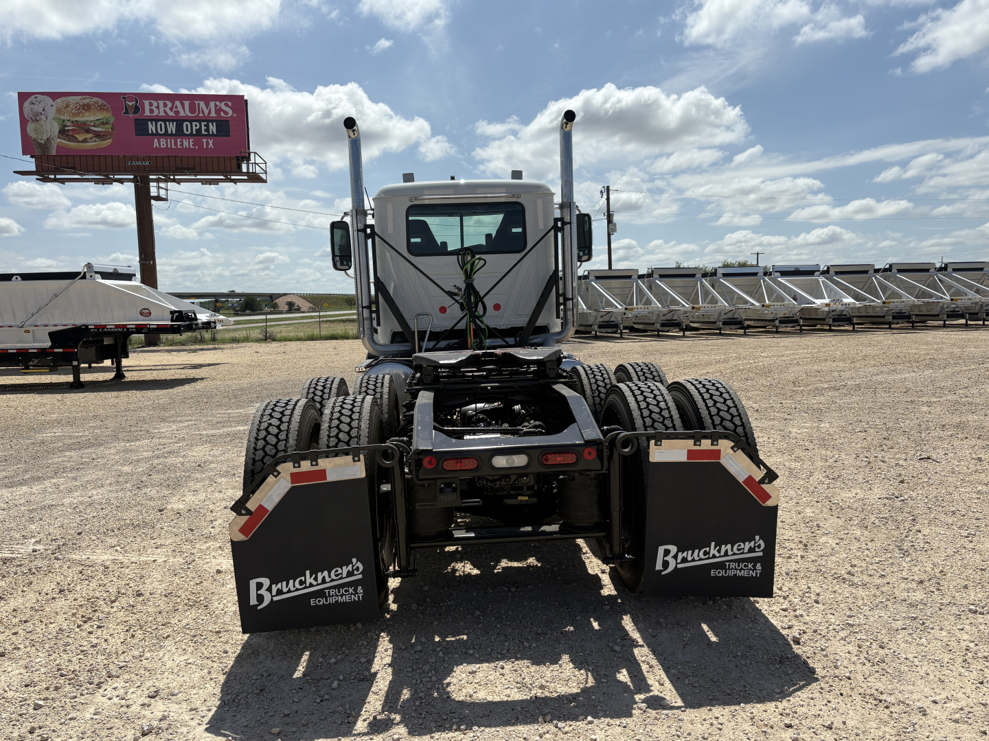 Front view of a 2027 Mack PI64T conventional daycab tractor showing dual rear axles and mudflaps with Bruckner's Equipment markings.