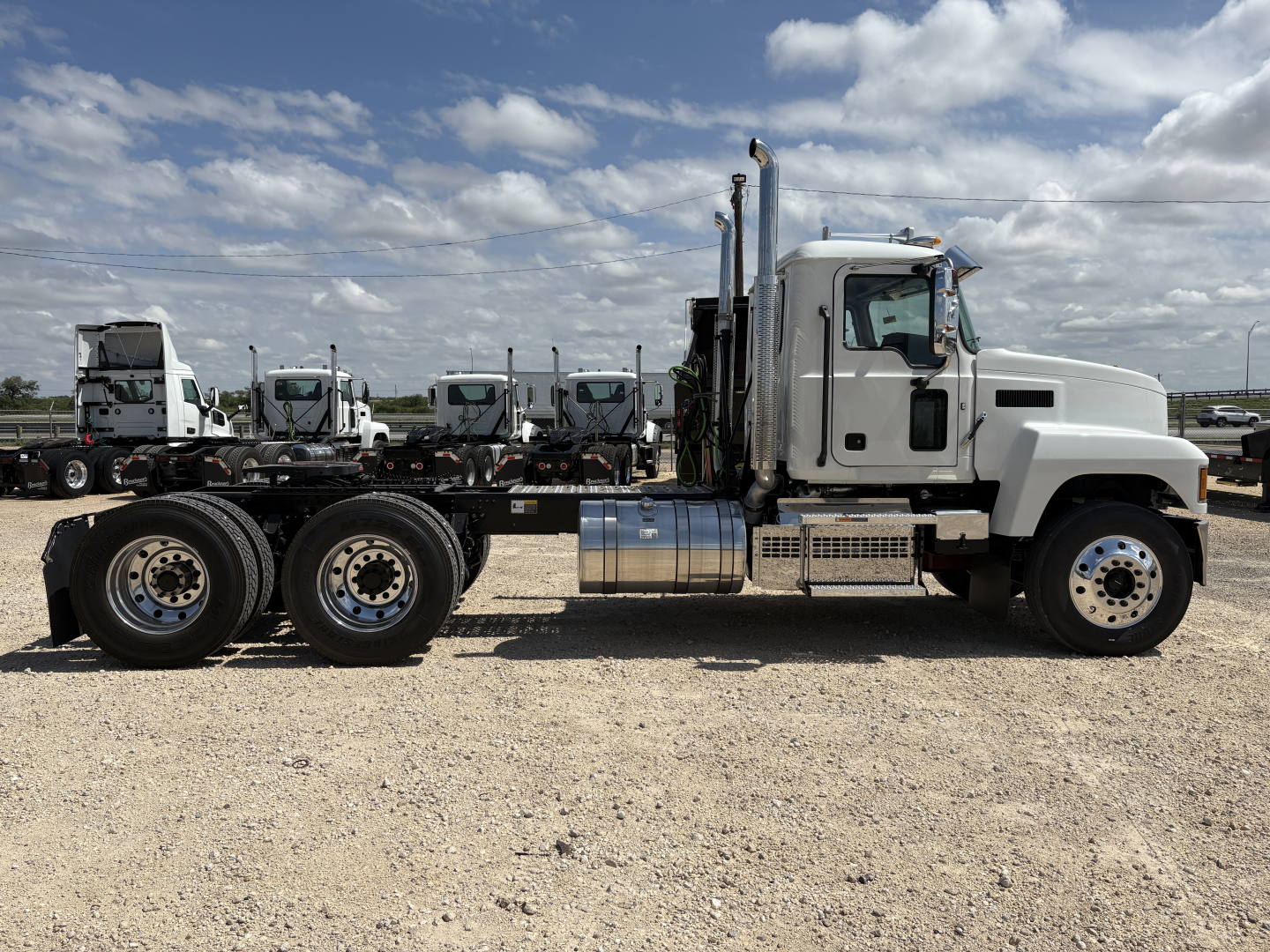 2027 Mack PI64T conventional daycab tractor side view showing cab, chrome fuel tanks, dual rear axles, and clean white paint.