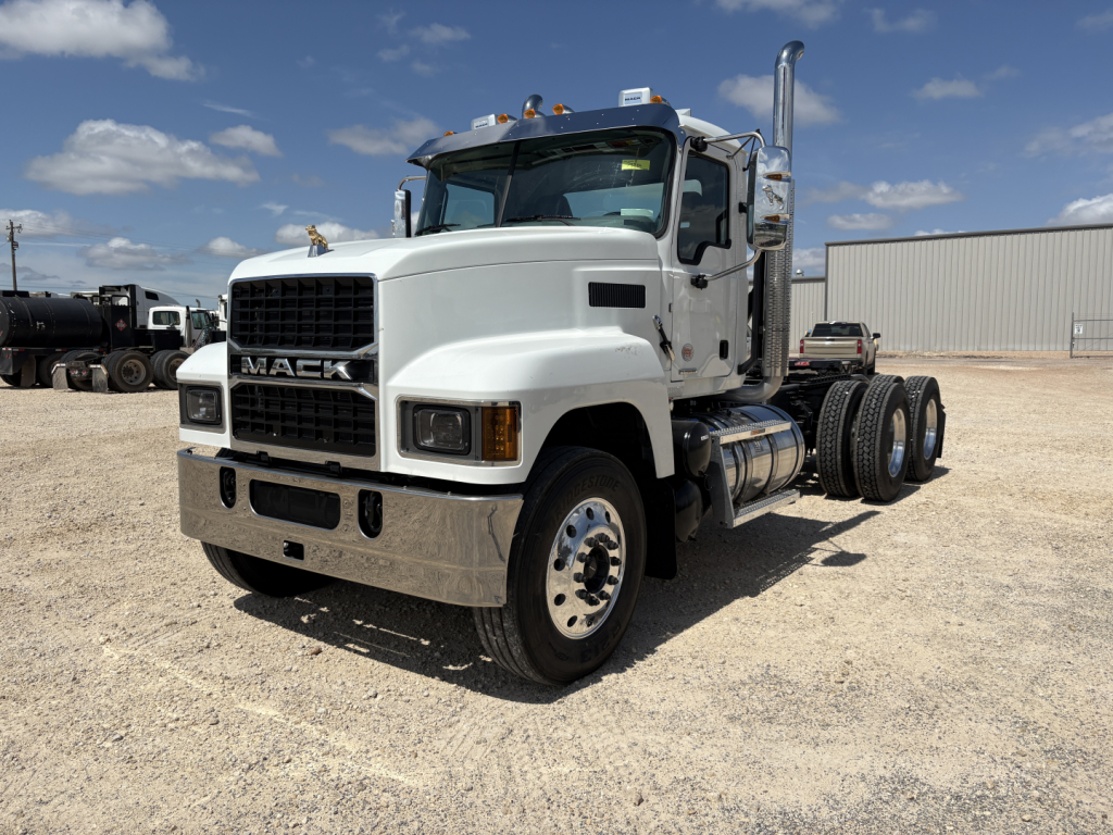 Mack PI64T tractor truck cab front-left view showing white exterior, large grille, dual exhaust stacks, and dual rear axles.