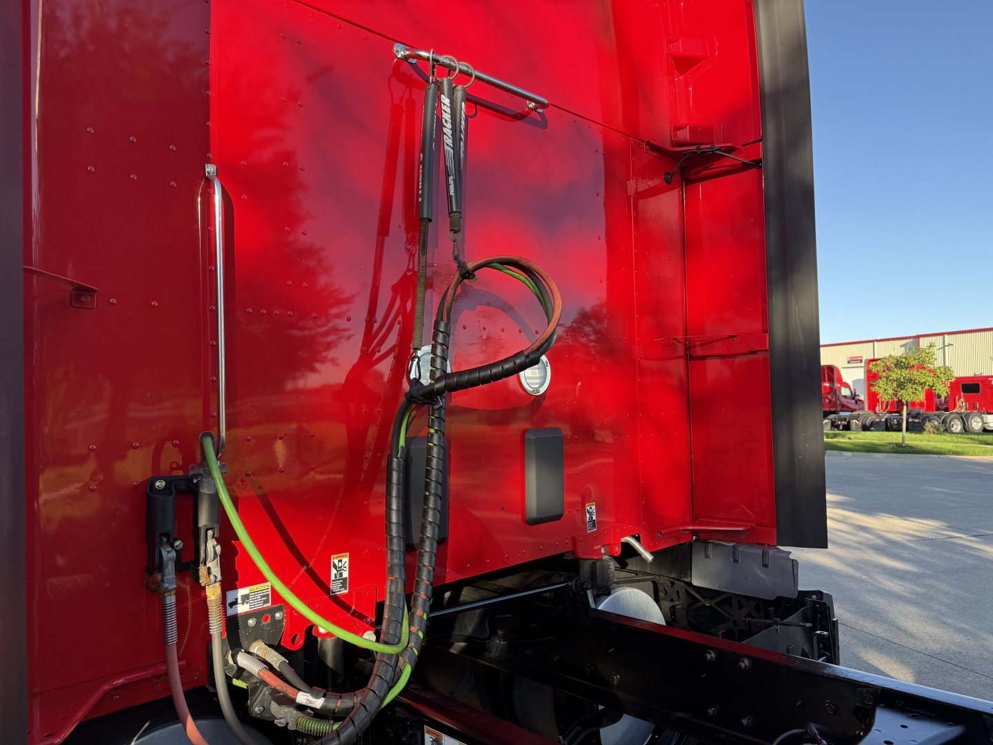 Kenworth T680 rear/side of sleeper showing hydraulic hoses, electric cables and connector fittings mounted on red truck body.