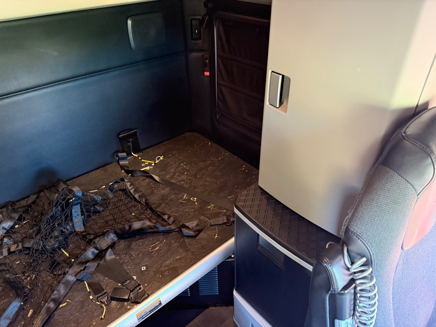 Kenworth T680 sleeper cab interior with scattered wiring and debris on the floor of the cargo area.