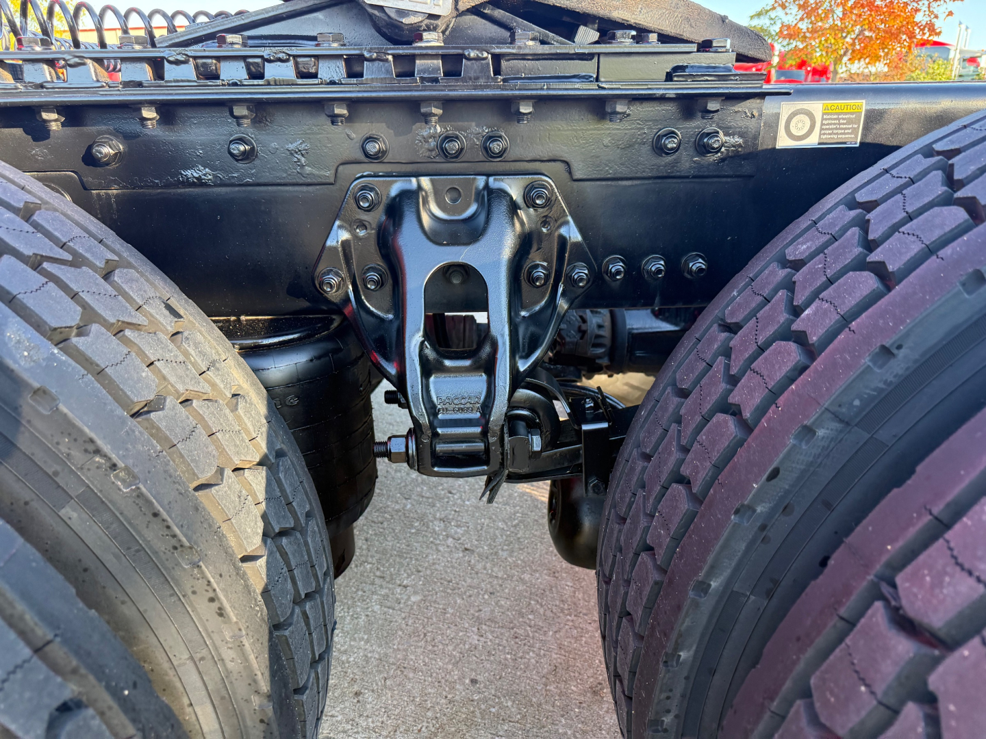 Kenworth T680 chassis view showing rear axle mounting and air lines/guides between dual rear tires.