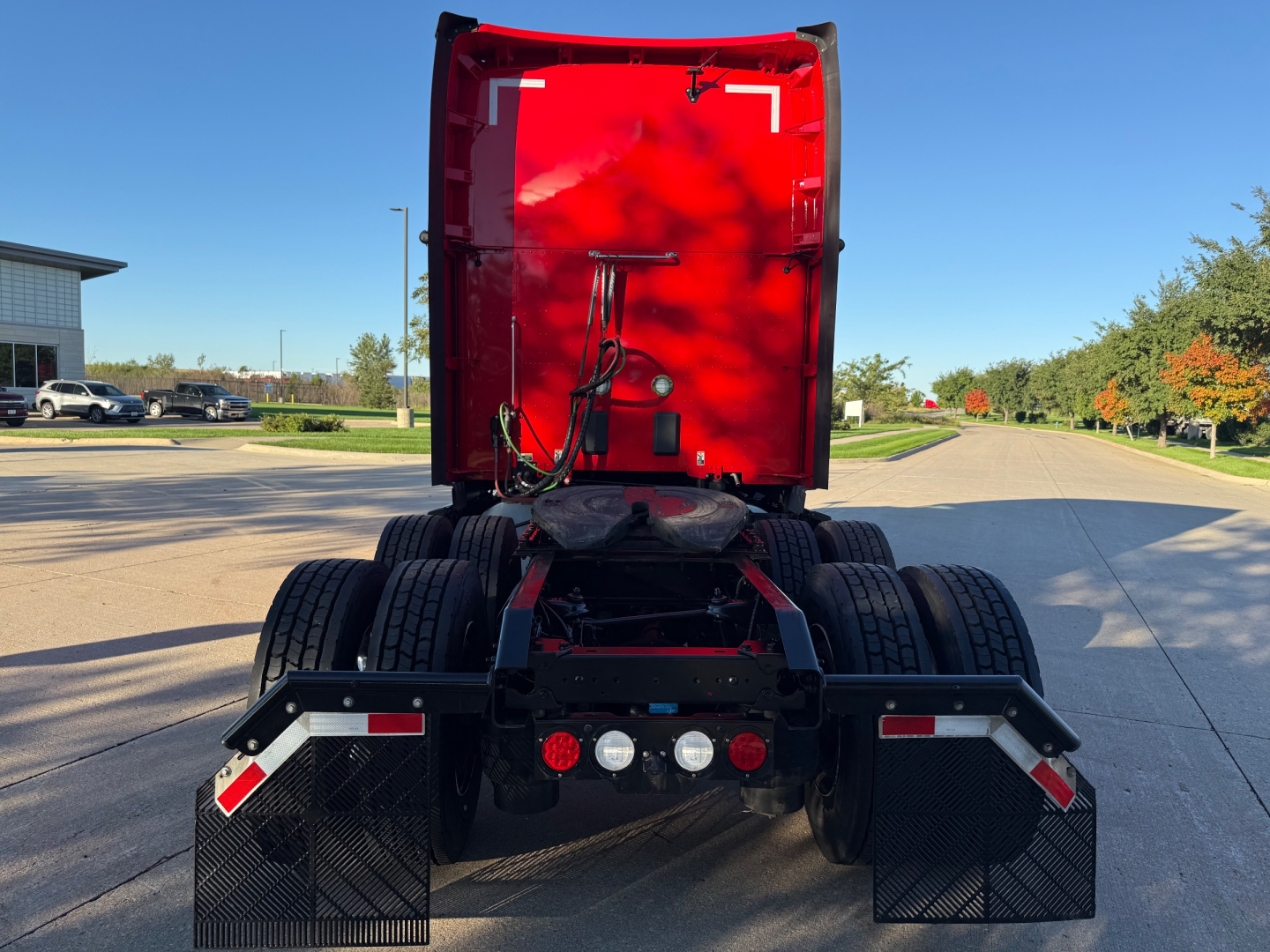 Kenworth T680 truck rear view showing fifth wheel area and twin rear axles with mud flaps and taillights in a parking lot.
