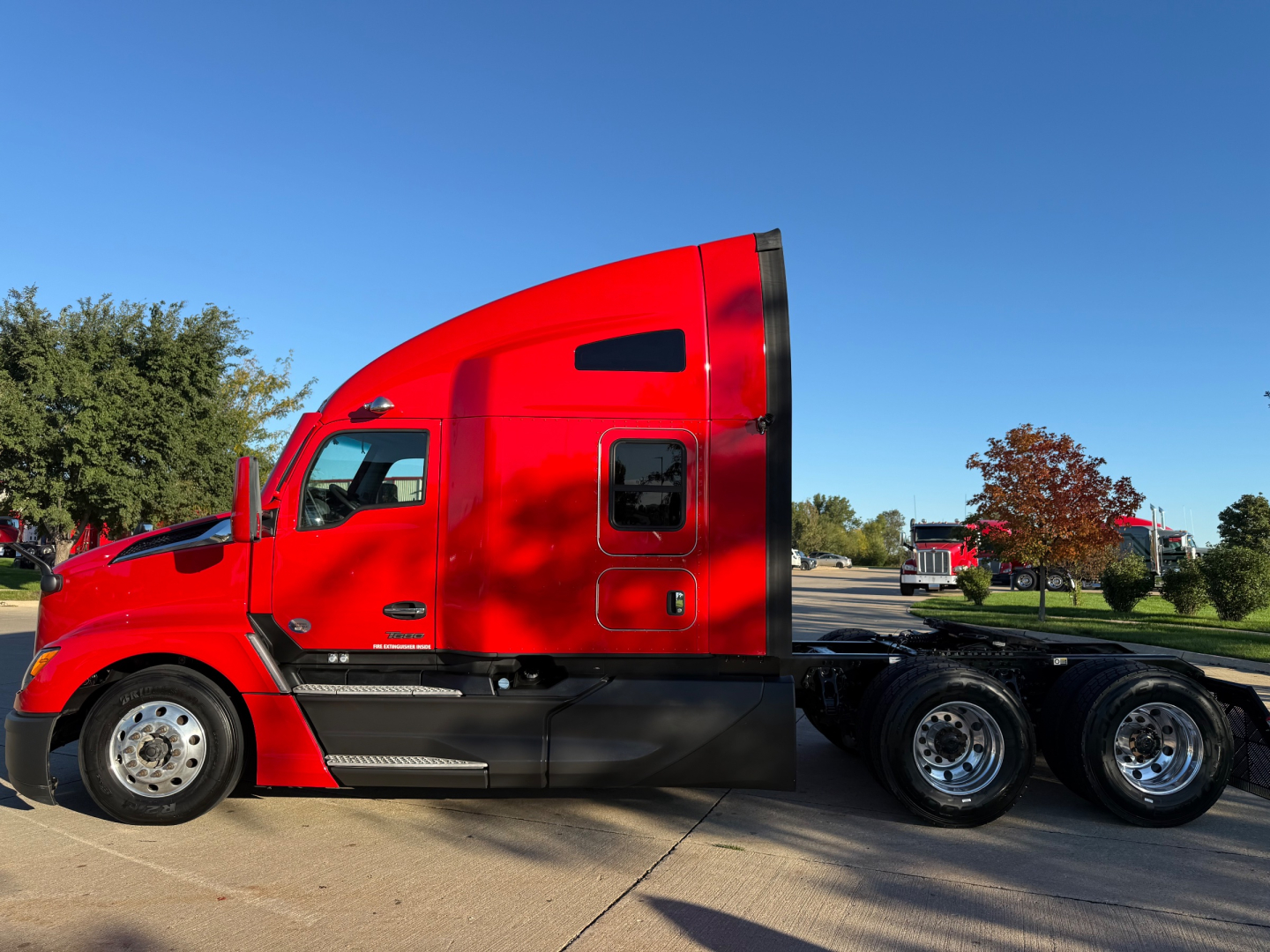 Kenworth T680 side view with red cab, sleeper, and triple rear axles; no visible text or labels.