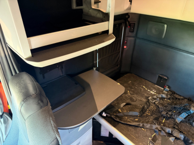 Kenworth T680 cab interior showing bunk area and storage shelves with a fold-out table.