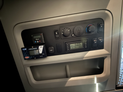 Kenworth T680 dash area showing climate controls, radio, and USB/aux panel; fuel gauge and storage pocket visible.