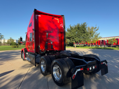 Kenworth T680 tractor rear and sleeper cab, red with dual rear axles, various posters in background.