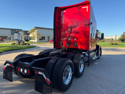 Semi-truck rear view showing red sleeper cab and multi-axle rear with tires and mud flaps.