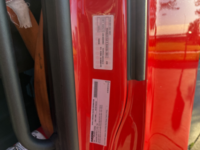 Kenworth T680 door area with VIN sticker and stock number label on red cab, visible text includes VIN 1XKYD49X1PJ229956 and stock tag.