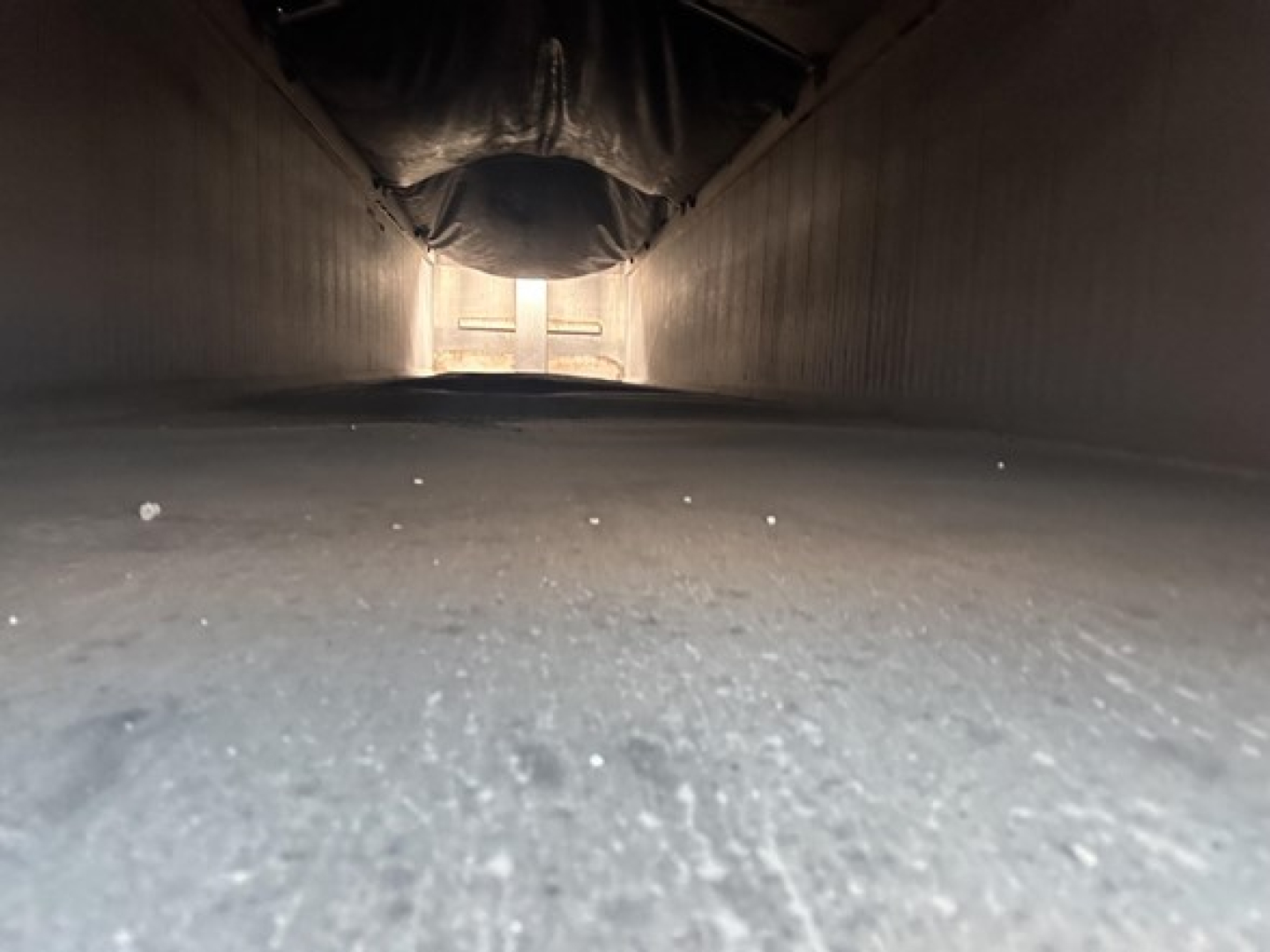 Trailer underside showing interior of dump trailer with smooth aluminum floor and side walls.