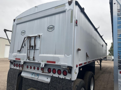 Trailer rear view showing Mac end dump frameless aluminum trailer with dual rear axles and multiple tail lights.