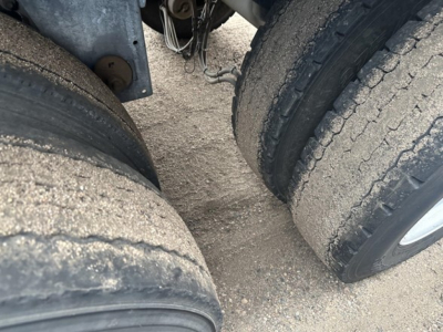 Mac MVP frameless aluminum end dump trailer wheel area showing dual rear axles and tire treads.