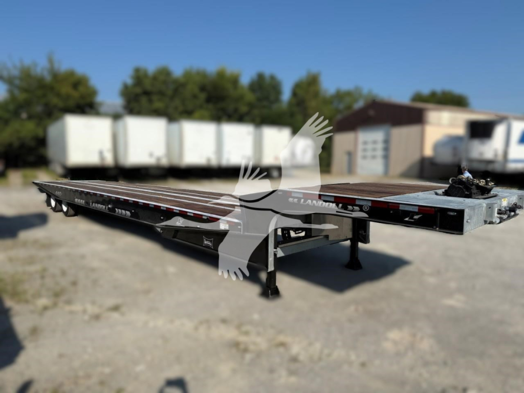 Landoll 440 trailer, long flatbed with dual tandem axles, deck plates, and wheel ramps visible; exterior showing VIN/stock area in a yard.