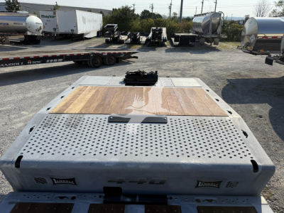 Landoll 440 trailer deck with perforated steel surface, wooden center patch, and hitch mechanism visible; branding 'Landoll' on side panels.